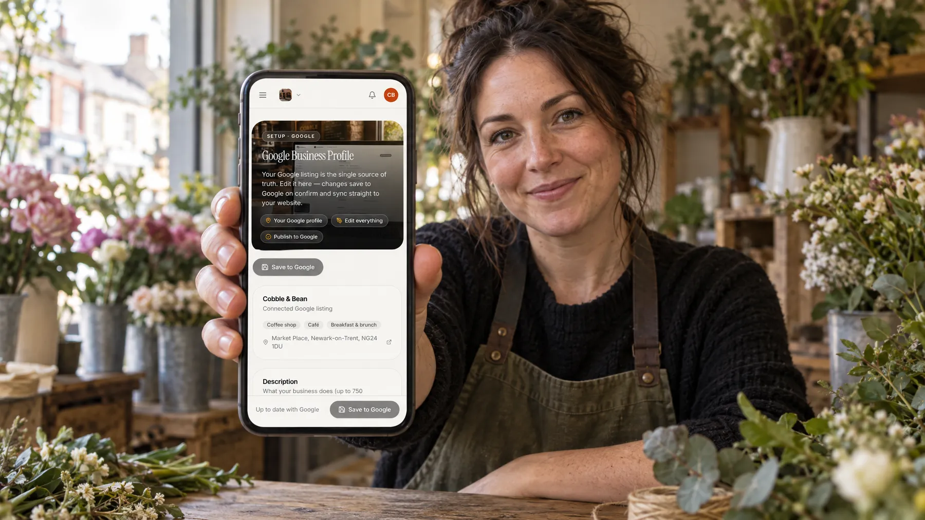 A florist in her shop holding up a phone that shows her Google Business Profile