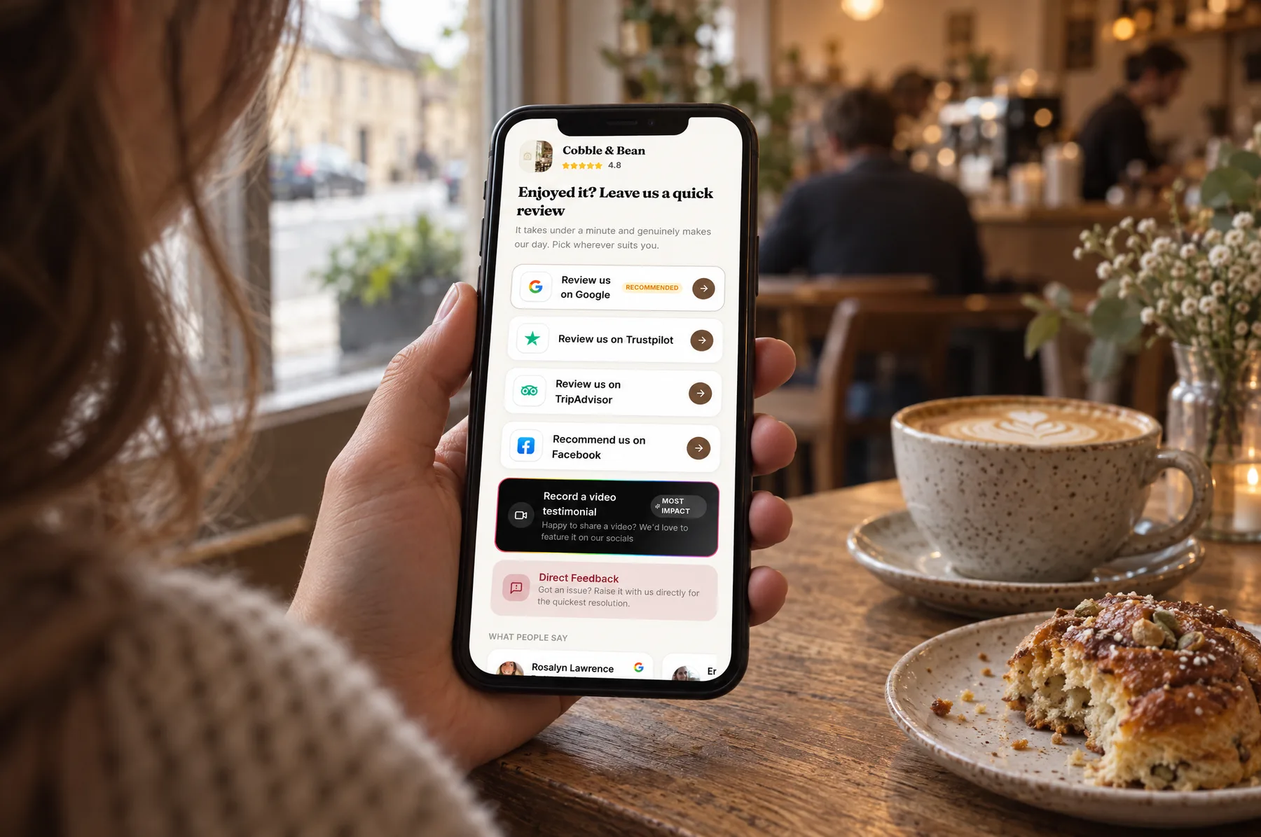 A customer leaving Cobble & Bean a review on their phone, next to a flat white